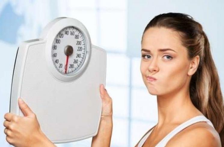 Perempuan menggunakan alat timbangan berat badan. (Shutterstock)