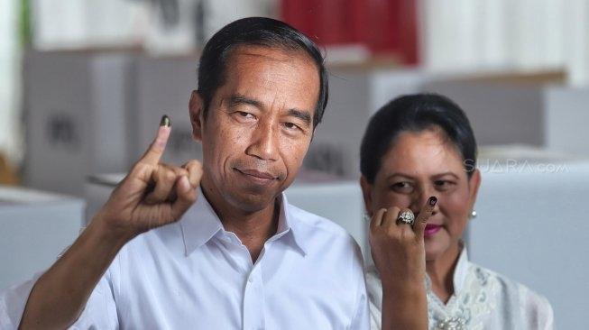Calon Presiden nomor urut 01 Joko Widodo menggunakan hak suaranya bersama sang istri, Iriana Joko Widodo, di TPS, Jakarta Pusat, Rabu (17/4/2019). (Suara.com/Muhaimin A Untung)
