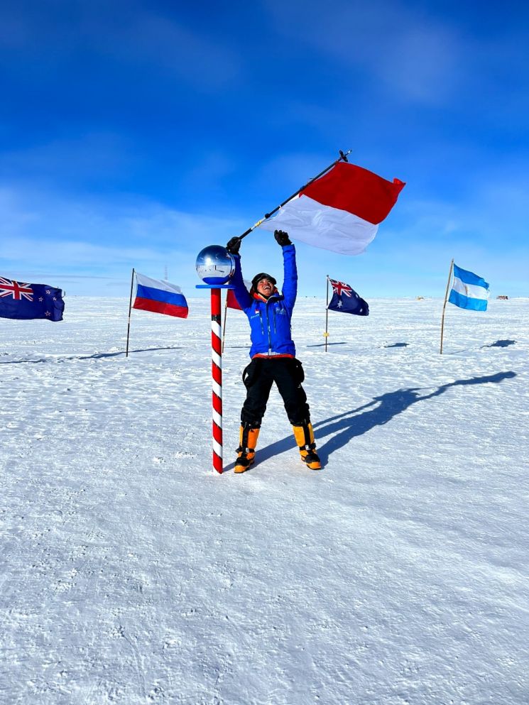 Putri Handayani melakukan selebrasi dan mengucap syukur di titik Ceremonial South Pole yang biasa dimanfaatkan para penjelajah untuk melakukan selebrasi di antara bendera-bendera 12 negara penandatangan asal Perjanjian Antartika. (Foto: Istimewa)