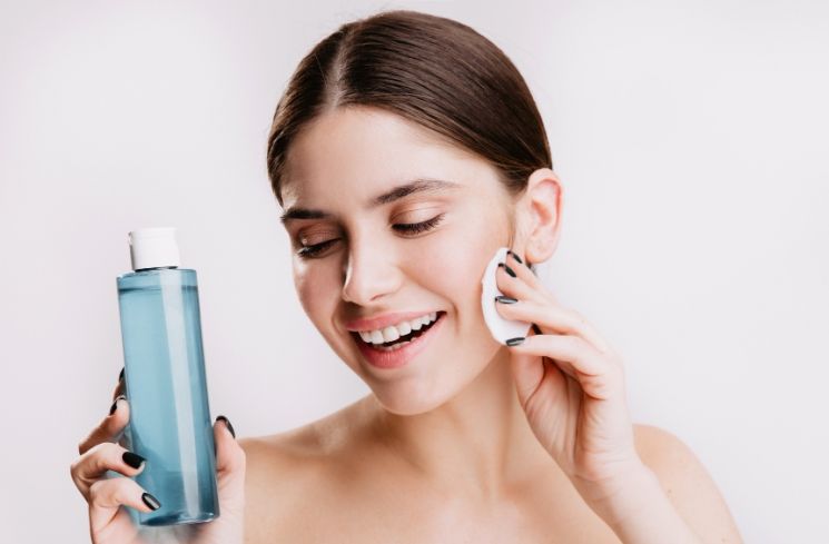 Ilustrasi perempuan membersihkan wajah dengan micellar water (Freepik/lookstudio)