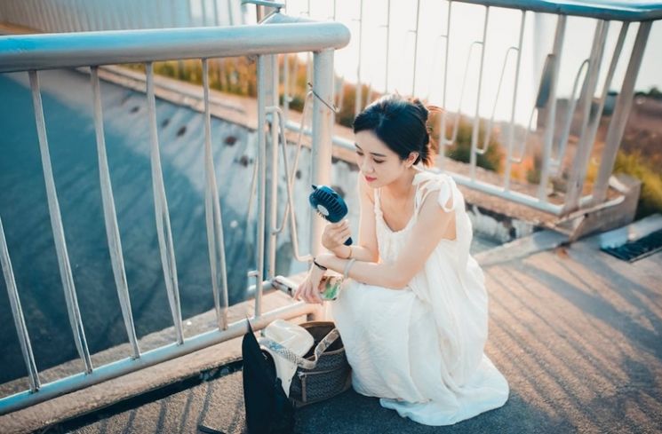 Ilustrasi memakai kipas angin portabel mini (Pexels.com/jason hu)
