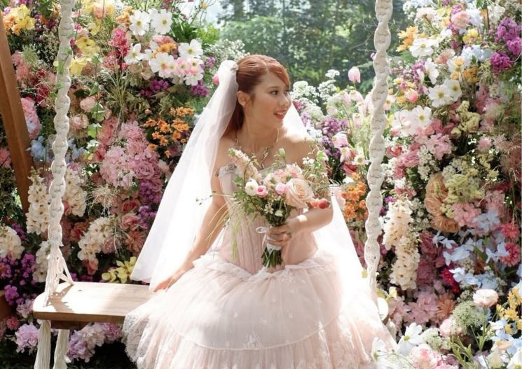 Potret Nadin Amizah dengan deretan bunga warna-warni yang menghiasi dekorasi resepsi (Instagram/@wirantikurniabride)